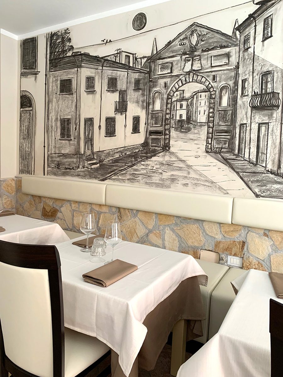 Il disegno a carboncino dell'arco e delle case del centro storico, sopra la panca della sala.